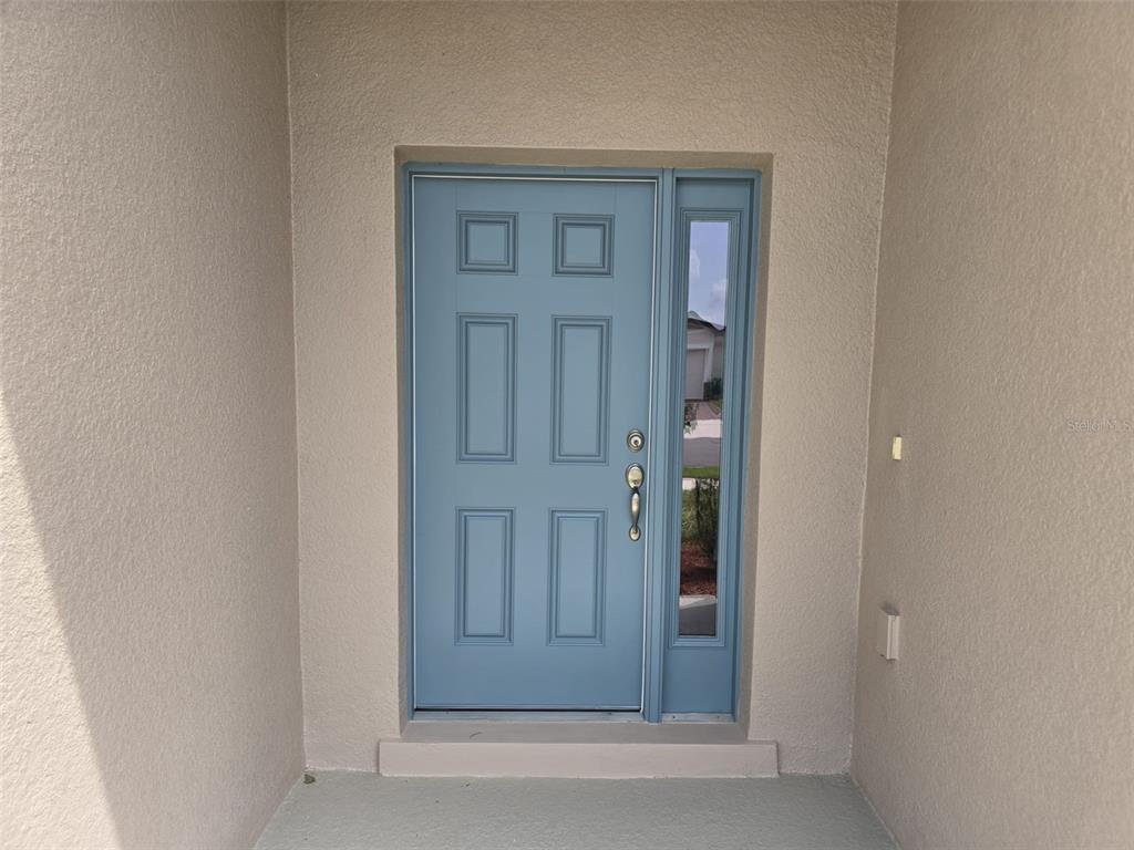 A light blue front door with a side window sits within a beige entryway — 5924 CATAMARAN AVENUE, HAINES CITY, FL