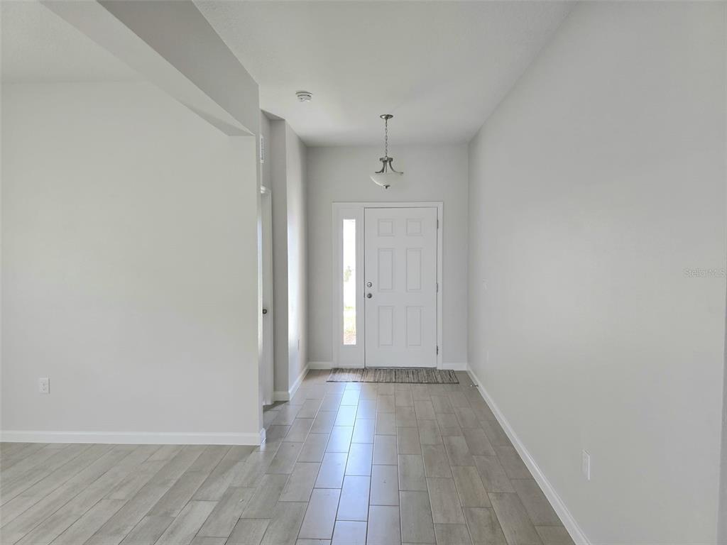A bright entryway features light gray walls, wood-look tile flooring, and a white front door — 5924 CATAMARAN AVENUE, HAINES CITY, FL