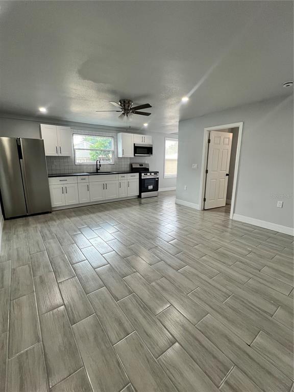 A kitchen with white cabinets, stainless steel appliances, and gray wood-look tile flooring — 2309 21ST AVENUE W, BRADENTON, FL