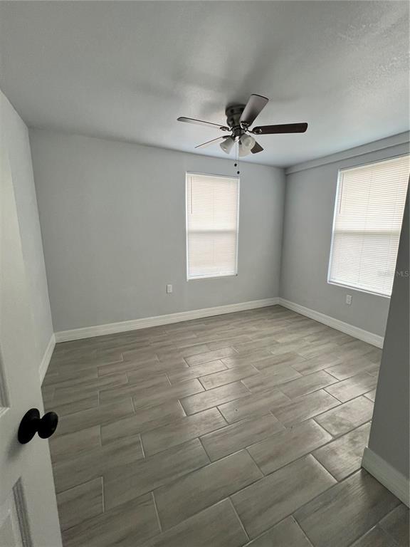 An empty bedroom features light gray walls, wood-look tile flooring, and a ceiling fan — 2309 21ST AVENUE W, BRADENTON, FL