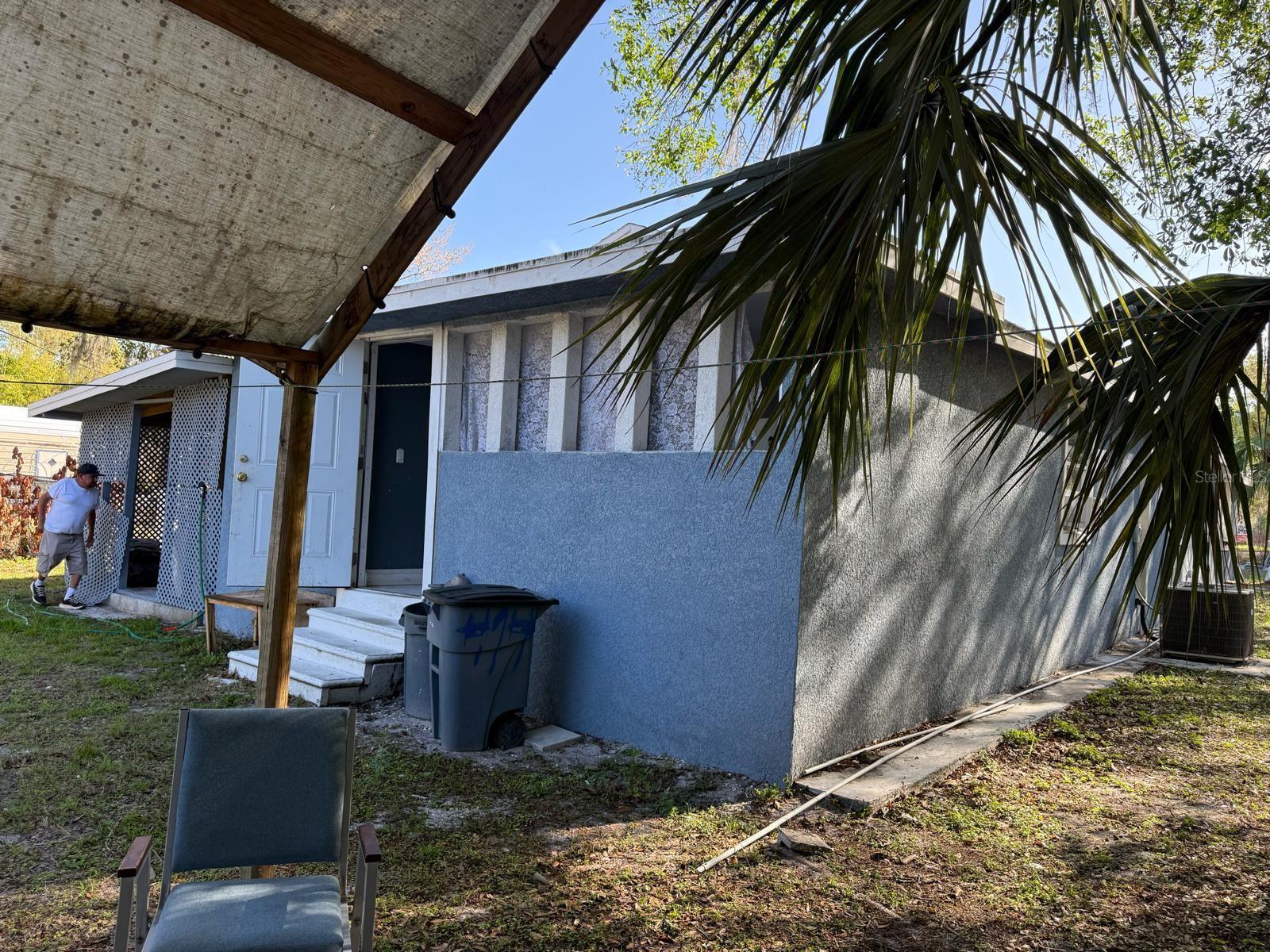A blue stucco exterior of a house with a small porch and a person nearby — 414 Spring Avenue, FL 34266, FL