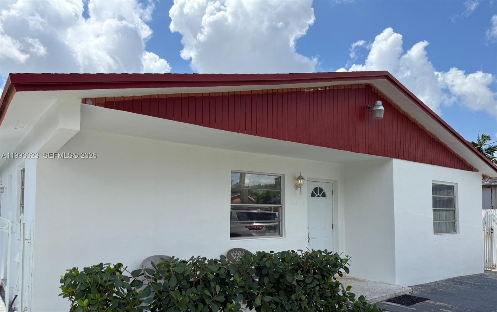 The exterior of a white house features a red-painted gable and a front entrance — 3066 NW 28th St, Miami FL 33142, MIAMI, FL