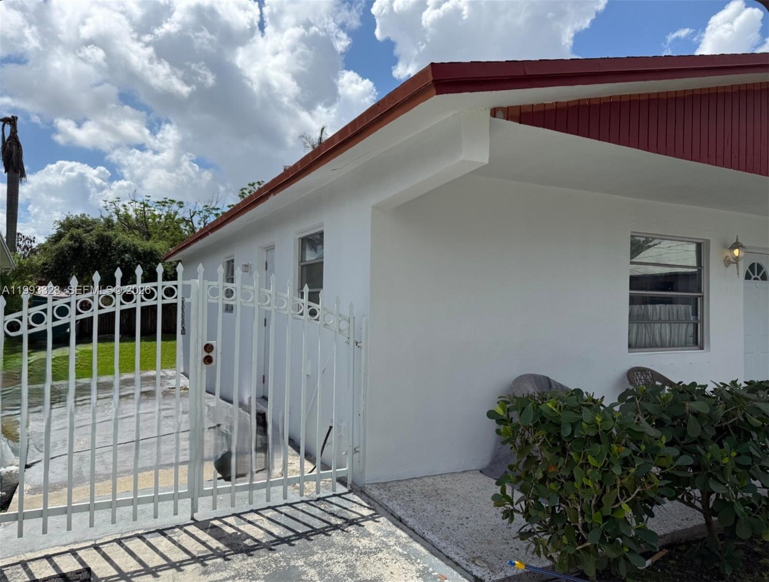 A white house with a red roof and a white metal gate in the foreground — 3066 NW 28th St, Miami FL 33142, MIAMI, FL