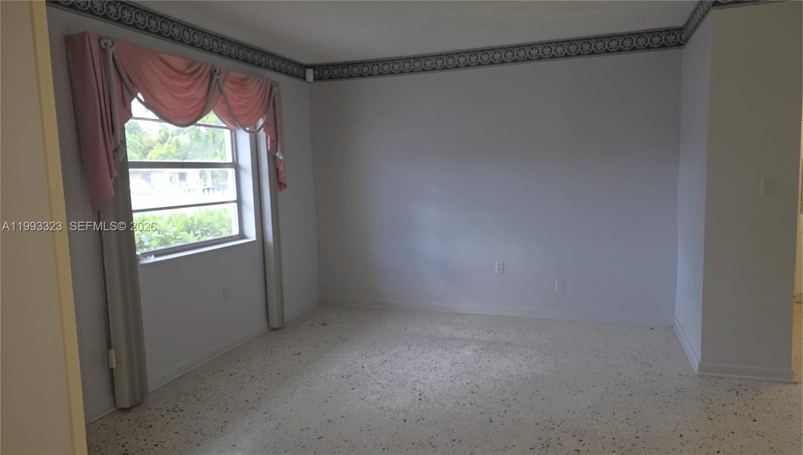 An empty room features light-colored walls, a window with pink valance curtains, and terrazzo flooring — 3066 NW 28th St, Miami FL 33142, MIAMI, FL