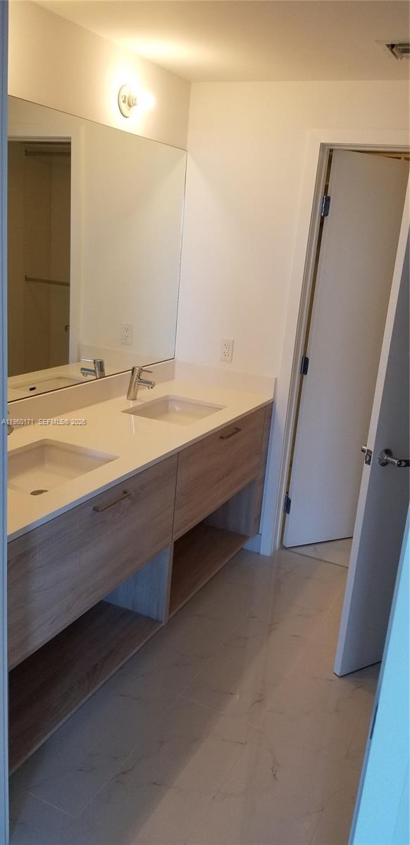 A bathroom features a double-sink vanity with light wood cabinets and a large wall mirror — 16385 Biscayne Blvd # 1516, Miami FL 33160, MIAMI, FL
