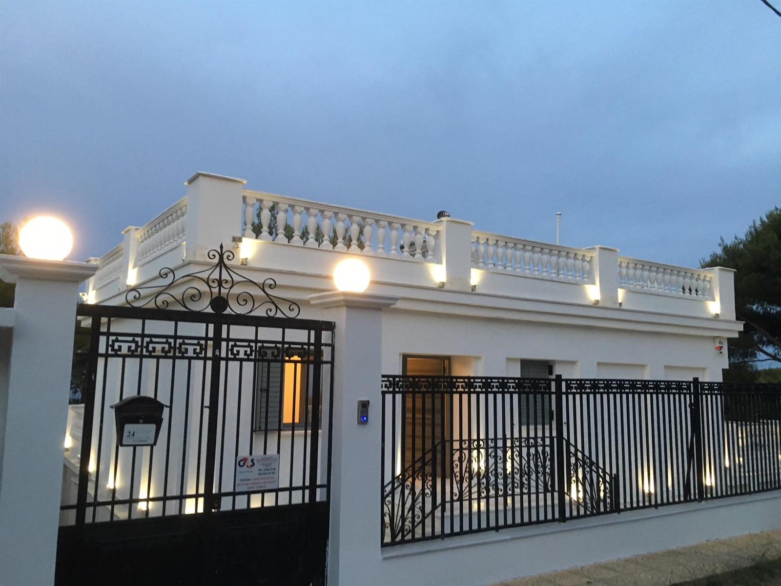 A white house with a balustrade roof terrace and black metal fencing at dusk — 23 Zefirou, Rafina, Greece, FL