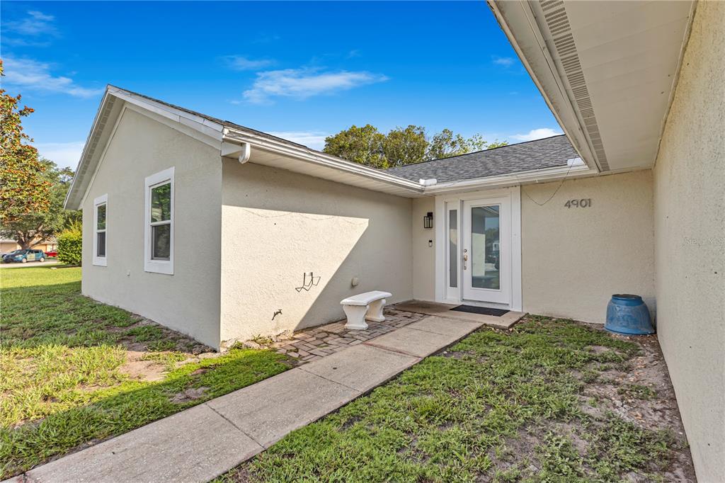 The exterior of a beige stucco house features a white front door and walkway — 4901 REGINALD ROAD, ORLANDO, FL
