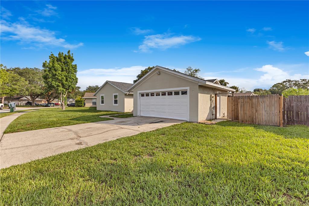 A single-story house with a white garage and a wooden fence on a grassy lot — 4901 REGINALD ROAD, ORLANDO, FL