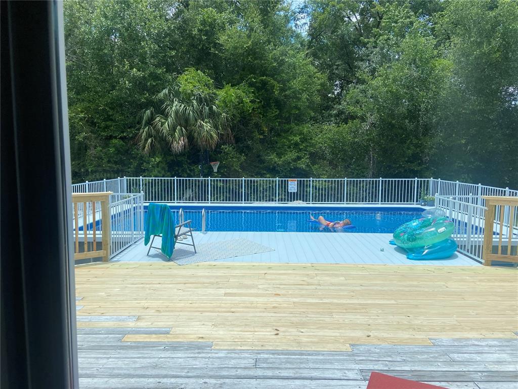 A backyard features a wooden deck leading to an above-ground swimming pool with white fencing — 876 MENTON ROAD, PIERSON, FL