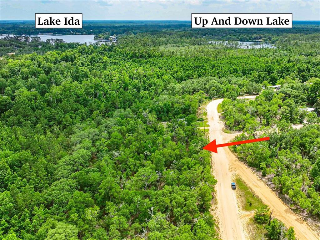 An aerial view shows a dirt road running through a wooded area near two lakes — 128 CARMICHAEL ROAD, INTERLACHEN, FL