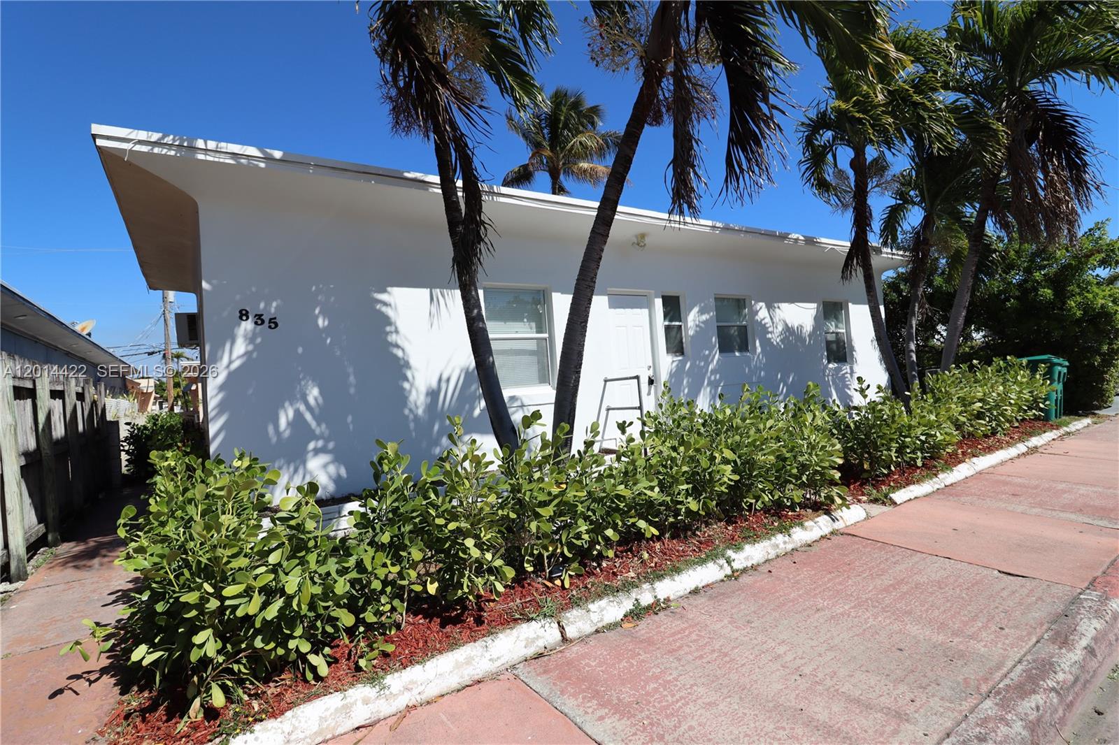 A white, single-story building with palm trees and a hedge sits beside a sidewalk — 835 83rd St, Miami Beach FL 33141, MIAMI BEACH, FL
