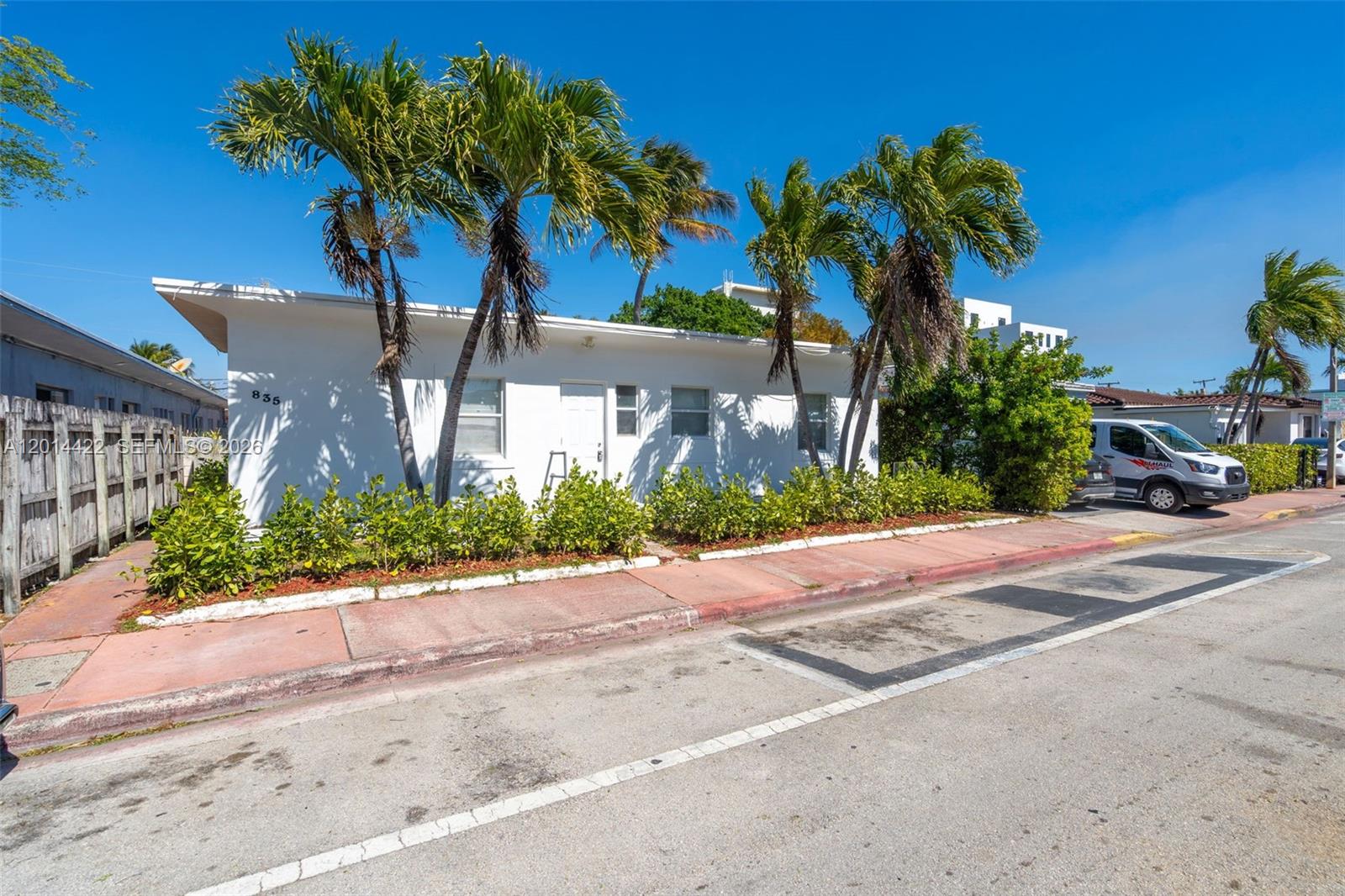 A white single-story building with palm trees and a small hedge sits beside a street — 835 83rd St, Miami Beach FL 33141, MIAMI BEACH, FL