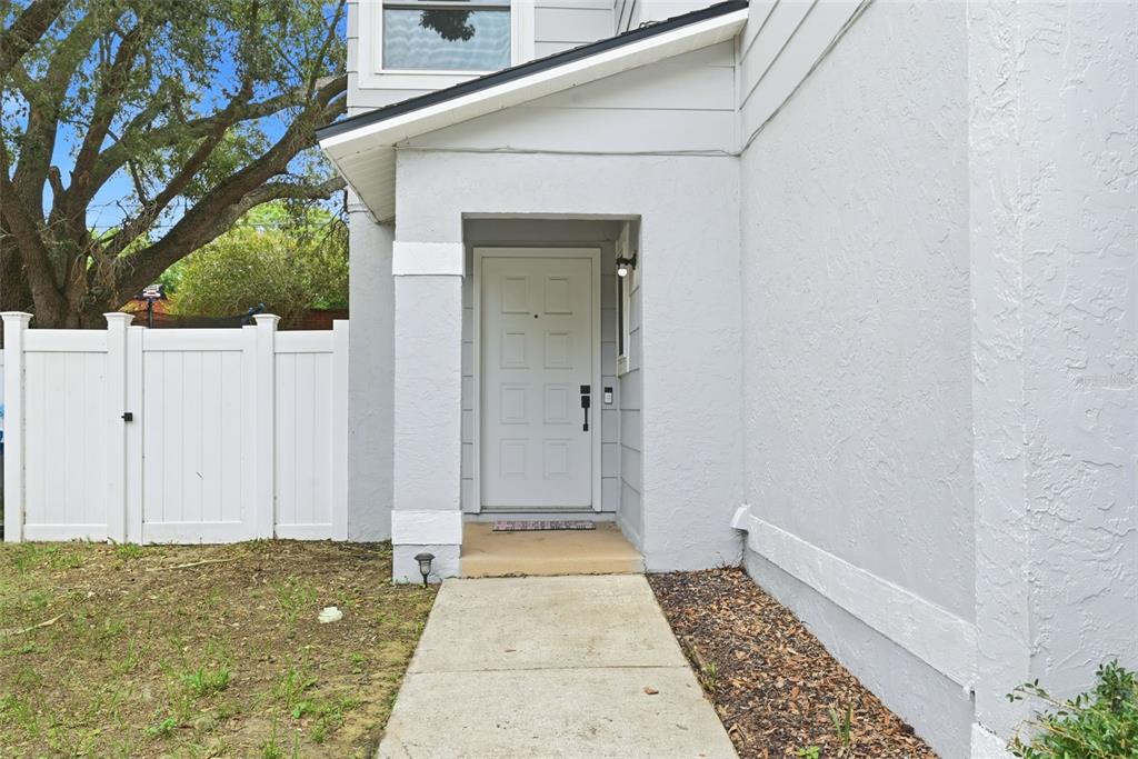 A concrete walkway leads to the white front door of a gray house with siding — 7215 HARBOR HEIGHTS CIRCLE, ORLANDO, FL