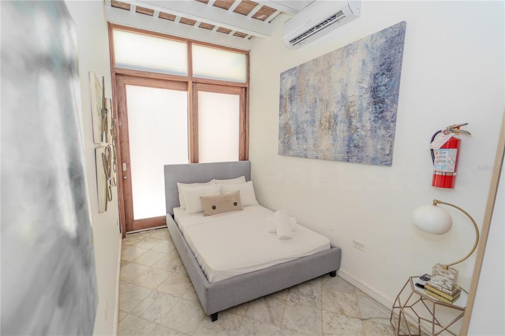 A bedroom features a gray bed, tiled floors, a large abstract painting, and a glass door — 152 SOL STREET, OLD SAN JUAN, PR