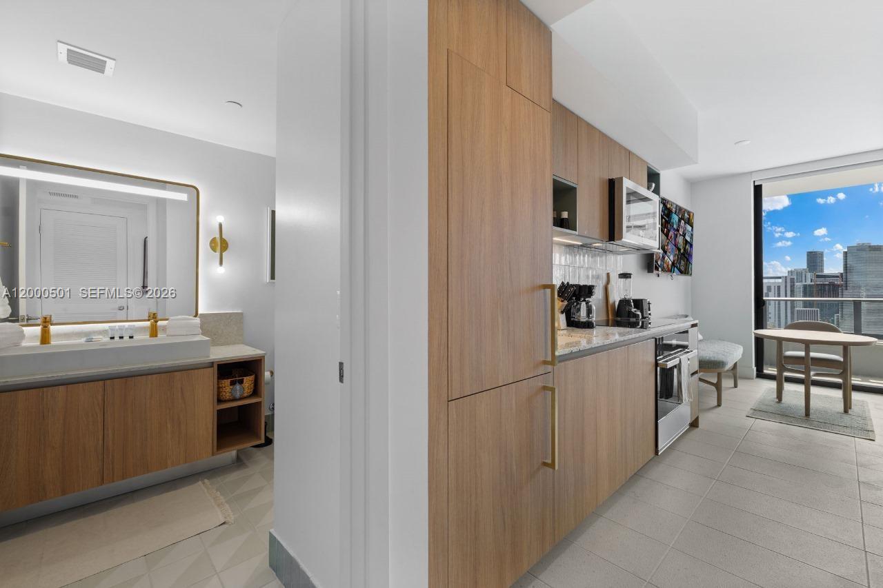 A modern kitchen with wood cabinetry and a bathroom with a vanity are visible — 159 NE 6 ST ST # 3206, Miami FL 33132, MIAMI, FL
