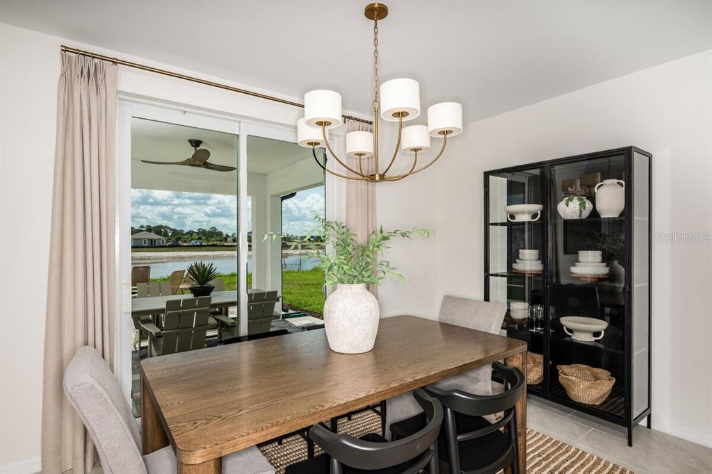 A dining room features a wooden table, a chandelier, and a glass-front cabinet near sliding doors — 9617 VIBRANT LANE, VENICE, FL