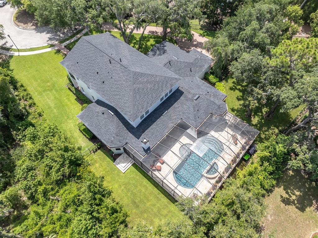 An aerial view shows a two-story house with a screened-in pool and surrounding wooded landscape — 16301 DUNLINDALE DRIVE, LITHIA, FL