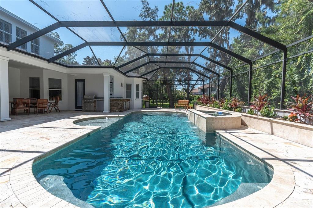 A screened-in swimming pool and spa with a stone patio and outdoor kitchen area — 16301 DUNLINDALE DRIVE, LITHIA, FL