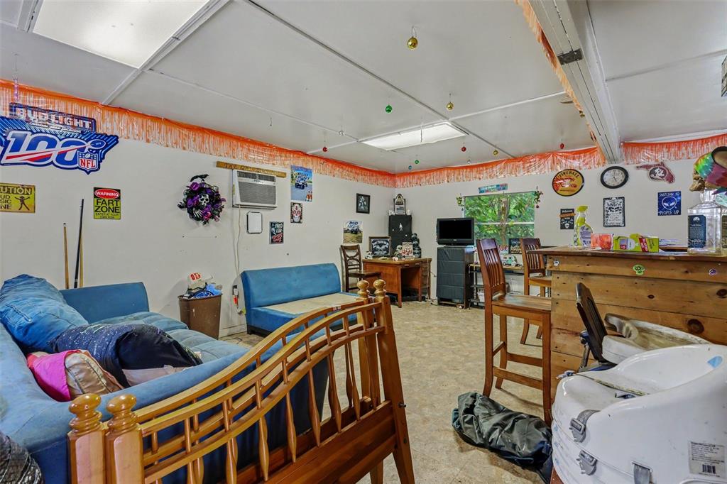 A casual room features a blue sofa, a wooden bar, and various wall decorations — 13395 SE 106TH AVENUE, OCKLAWAHA, FL