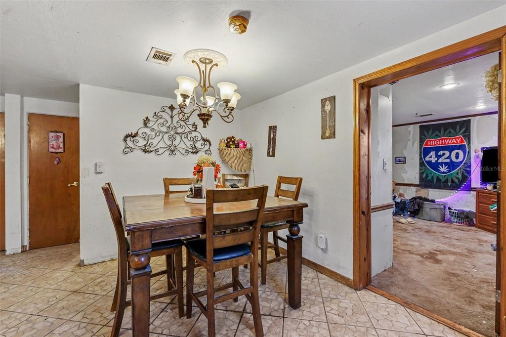 A dining room with a wooden table, chairs, tile flooring, and a chandelier — 13395 SE 106TH AVENUE, OCKLAWAHA, FL