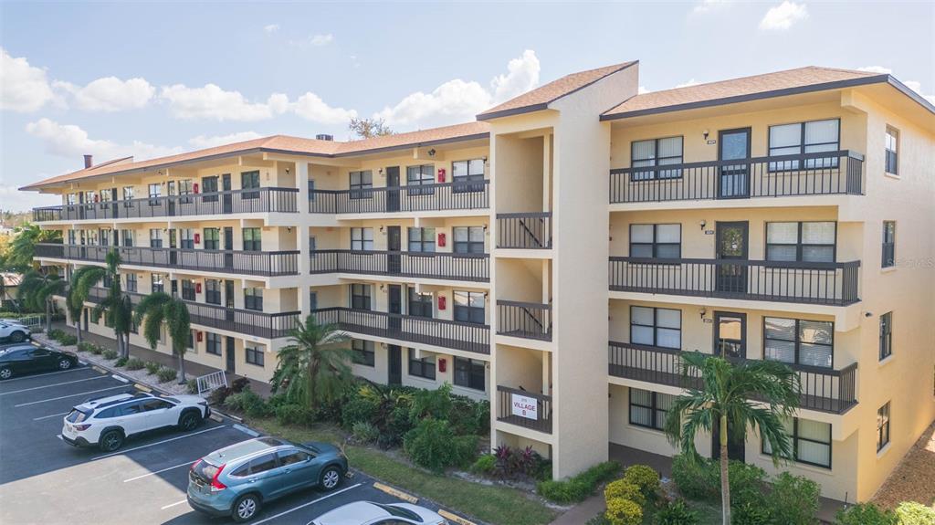 An exterior view of a multi-story apartment building with balconies and a parking lot — 315 30TH AVENUE W UNIT B201, BRADENTON, FL