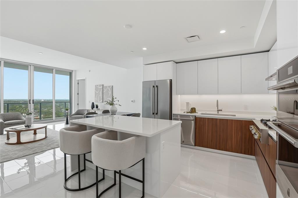 A modern kitchen features white upper cabinets, wood-toned lower cabinets, a central island, and balcony views — 400 CENTRAL AVENUE UNIT 2008, ST PETERSBURG, FL