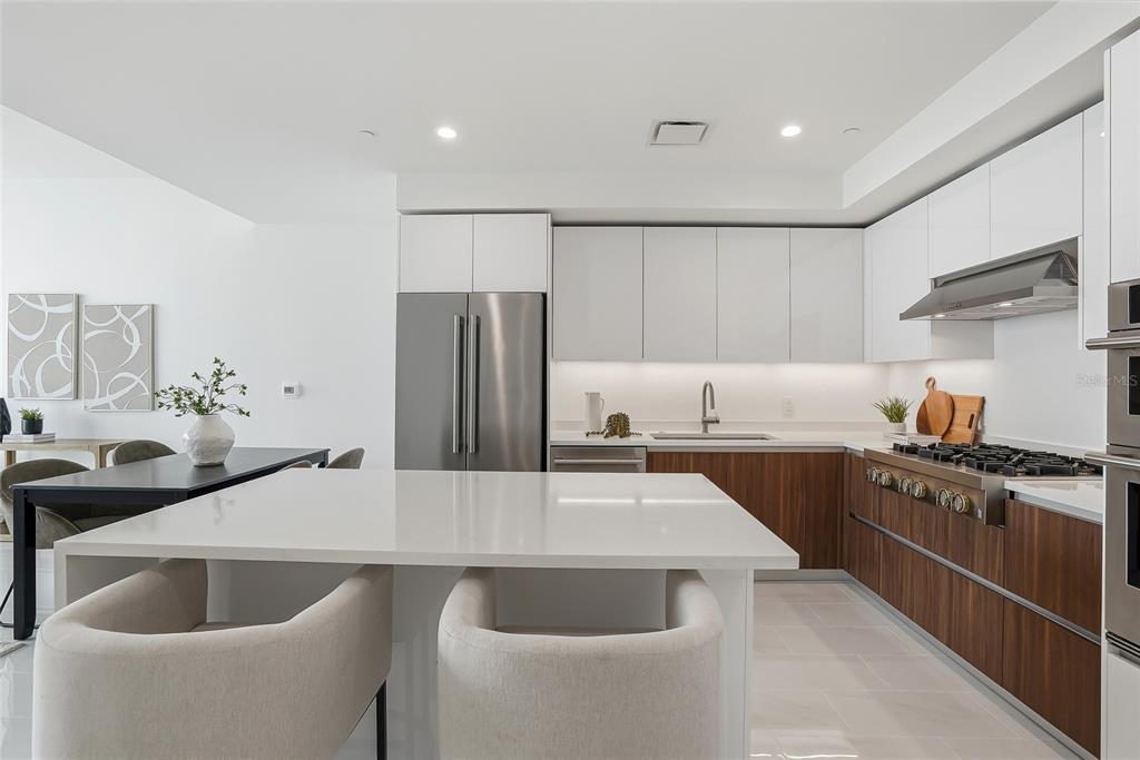 A modern kitchen features white upper cabinets, wood-grain lower cabinets, and a large quartz island — 400 CENTRAL AVENUE UNIT 2008, ST PETERSBURG, FL