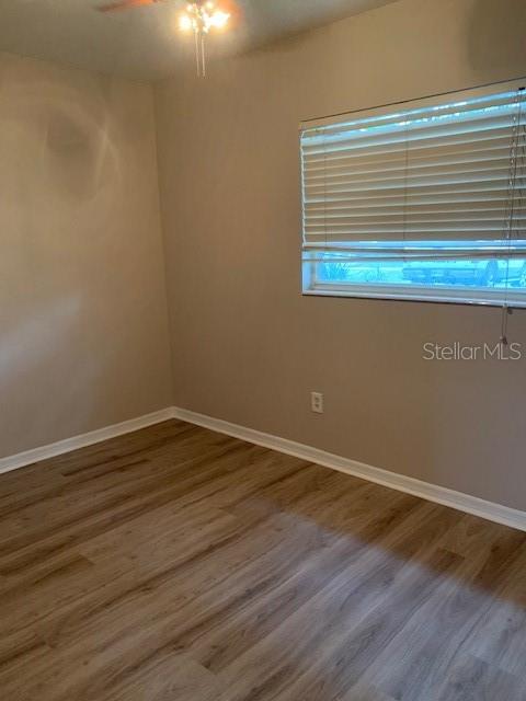 An empty bedroom features light-colored walls, wood-look flooring, and a window with horizontal blinds — 1940 64TH AVENUE N, ST PETERSBURG, FL