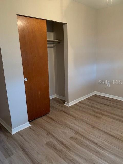 A room with light wood-look flooring, beige walls, and a wooden closet door — 1940 64TH AVENUE N, ST PETERSBURG, FL