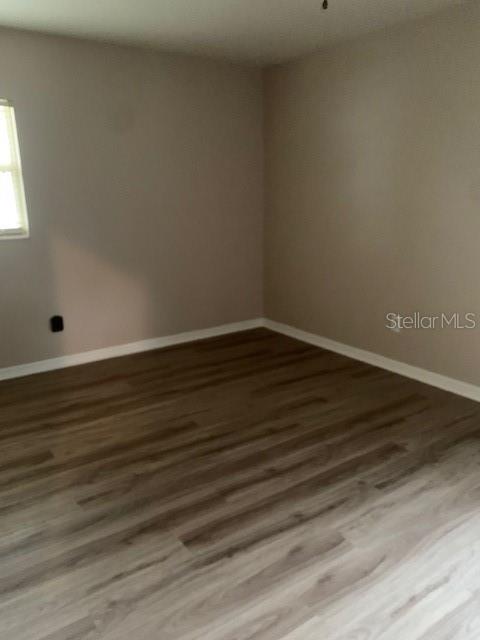 An empty room features light-colored walls, white baseboards, and wood-look laminate flooring — 1940 64TH AVENUE N, ST PETERSBURG, FL