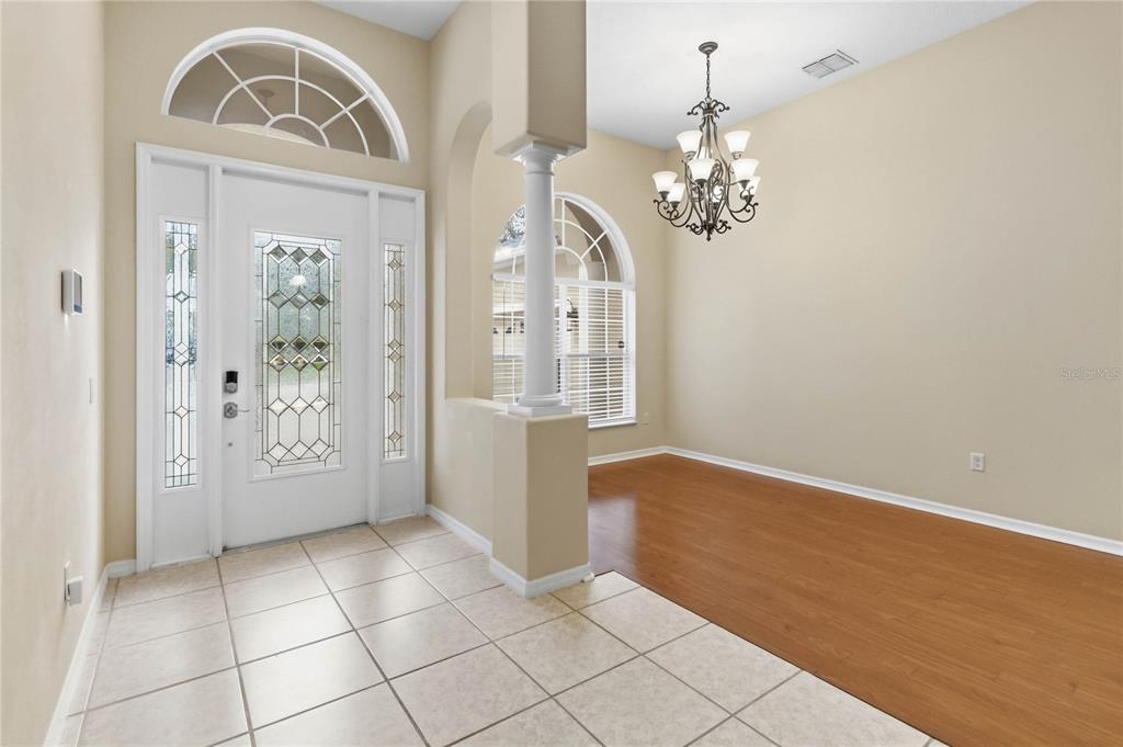 An entryway with tile flooring leads to a dining area featuring wood floors and chandelier — 513 PARKSIDE POINTE BOULEVARD, APOPKA, FL