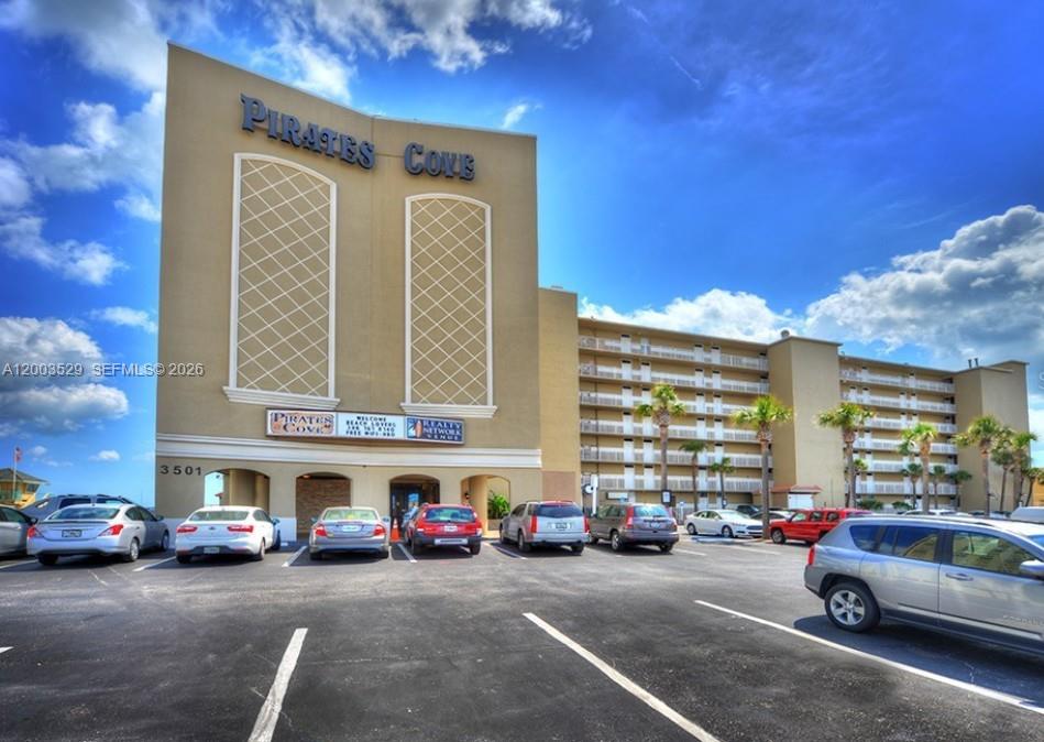 The exterior of a multi-story tan building with a parking lot in the foreground — 3501 S ATLANTIC AVE # G140, Daytona FL 32118, DAYTONA, FL
