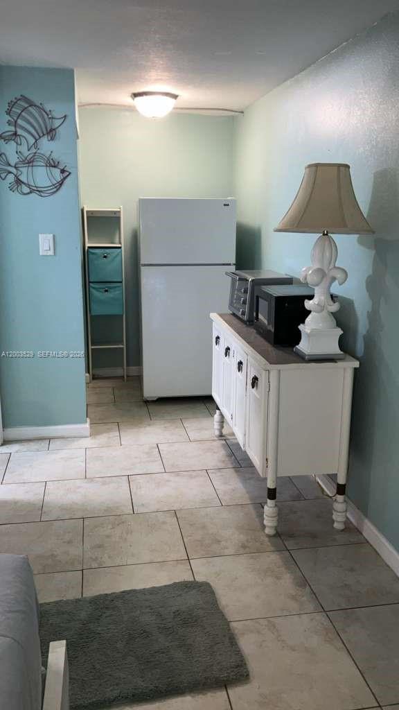 A kitchen area features a white refrigerator, a white sideboard with a lamp, and tile flooring — 3501 S ATLANTIC AVE # G140, Daytona FL 32118, DAYTONA, FL