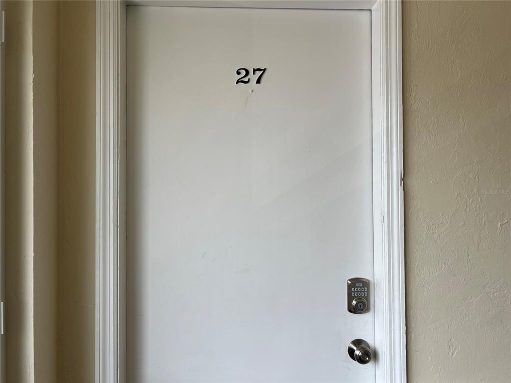A white door labeled with the number 27 features a digital keypad and a handle — 22481 WESTCHESTER BOULEVARD UNIT B27, PUNTA GORDA, FL
