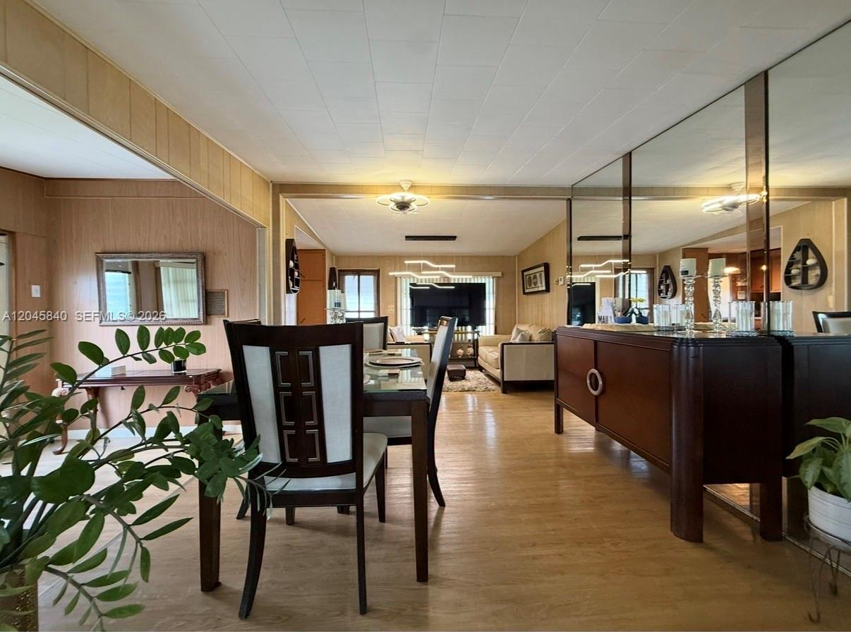 A dining area with wood-paneled walls leads into a living room with a large television — 3309 Orange ST, Hollywood FL 33021, HOLLYWOOD, FL