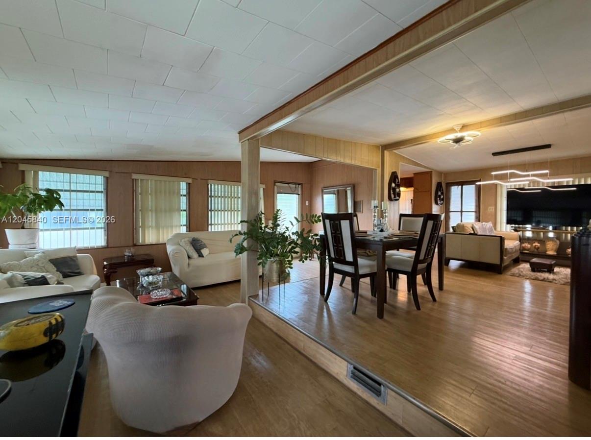 A living and dining area with wood-paneled walls, wood flooring, and a raised dining platform — 3309 Orange ST, Hollywood FL 33021, HOLLYWOOD, FL
