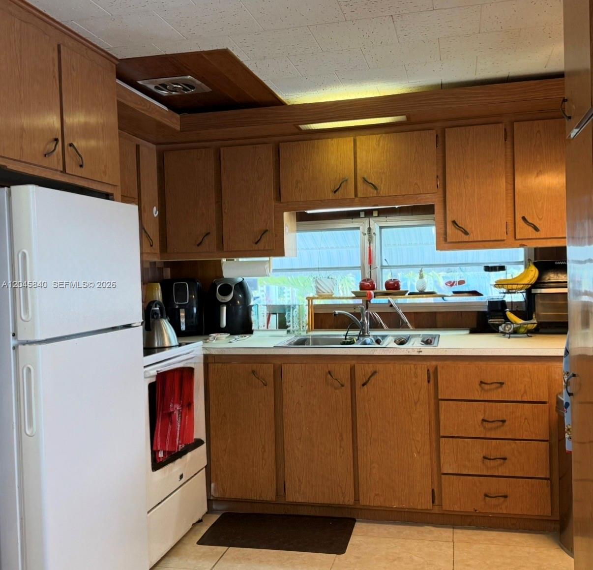 A kitchen features wood cabinets, white appliances, a sink, and a window above the counter — 3309 Orange ST, Hollywood FL 33021, HOLLYWOOD, FL