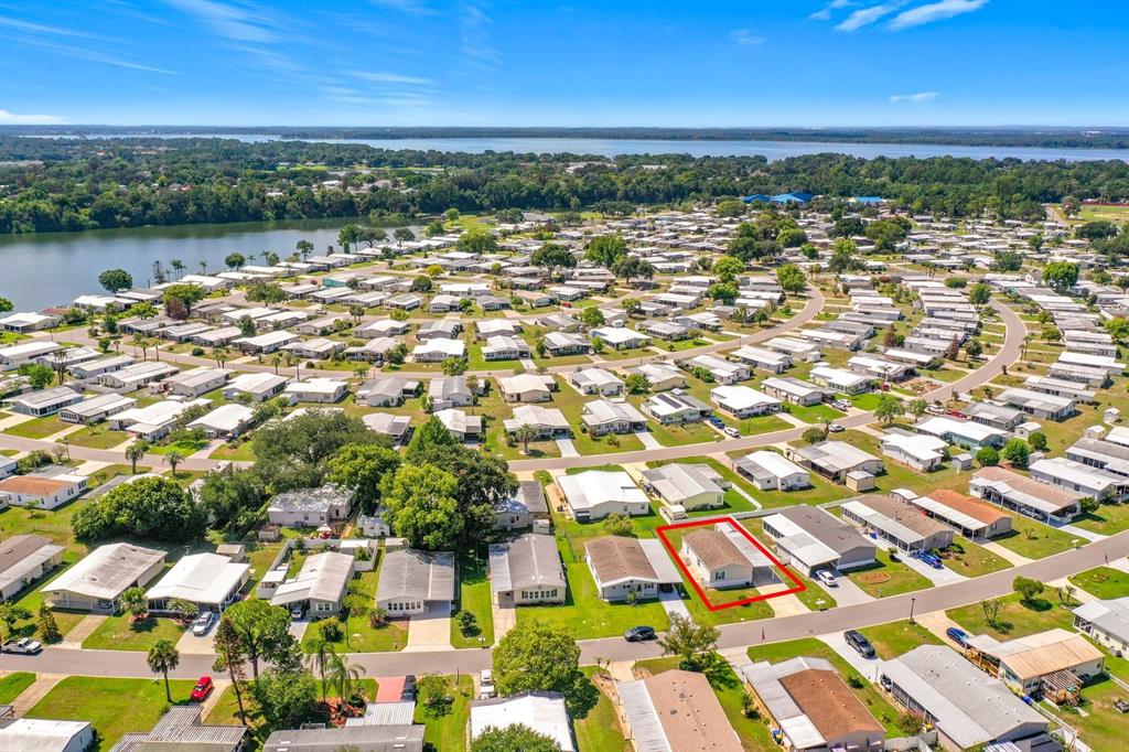 An aerial view shows a residential neighborhood of manufactured homes near a large lake — 1660 ELKHART CIRCLE, TAVARES, FL