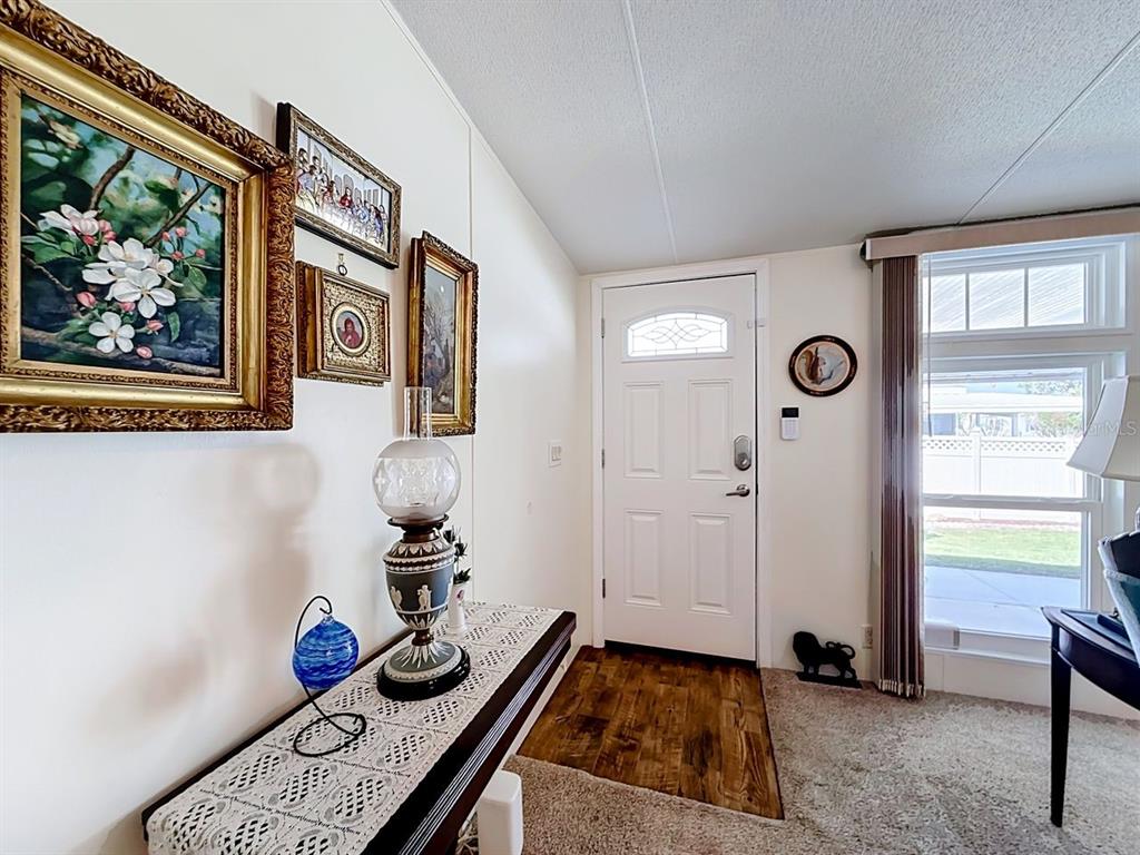 An entryway features a white door, wood-look flooring, a console table, and wall art — 1660 ELKHART CIRCLE, TAVARES, FL