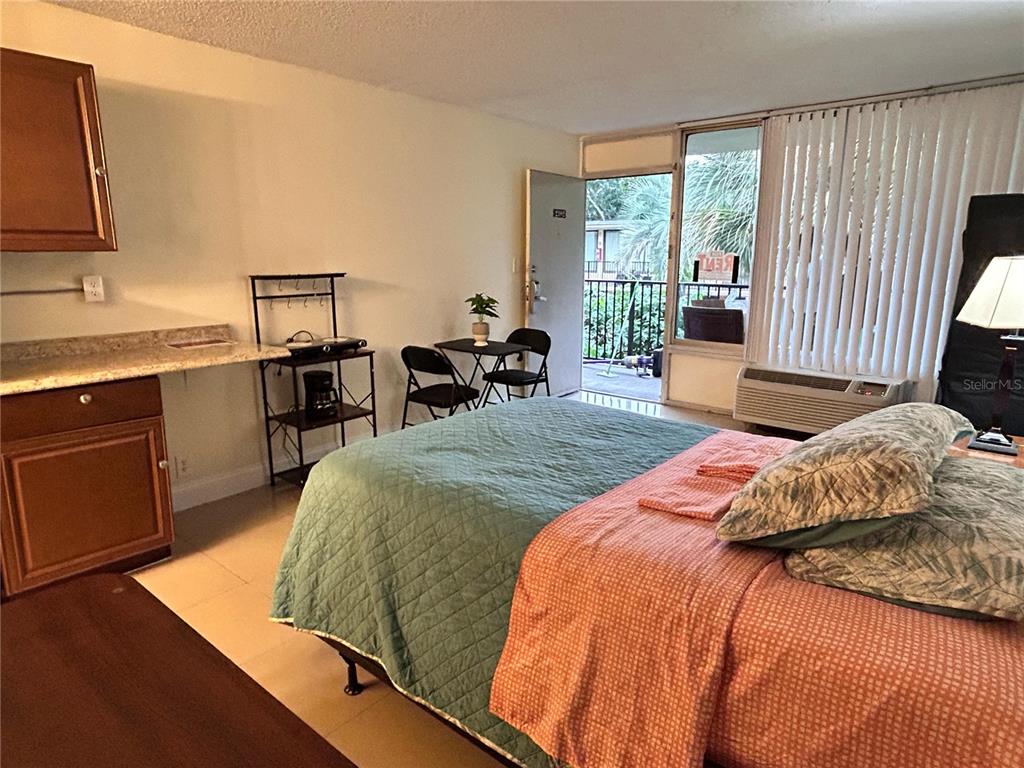 A studio apartment features a bed, a small dining set, and a kitchenette area — 7900 S ORANGE BLOSSOM TRAIL UNIT 2102, ORLANDO, FL