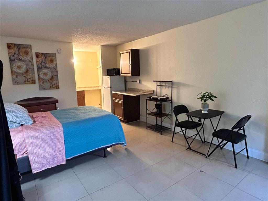 A studio apartment features a bed, a small kitchenette, and a dining table with chairs — 7900 S ORANGE BLOSSOM TRAIL UNIT 2102, ORLANDO, FL