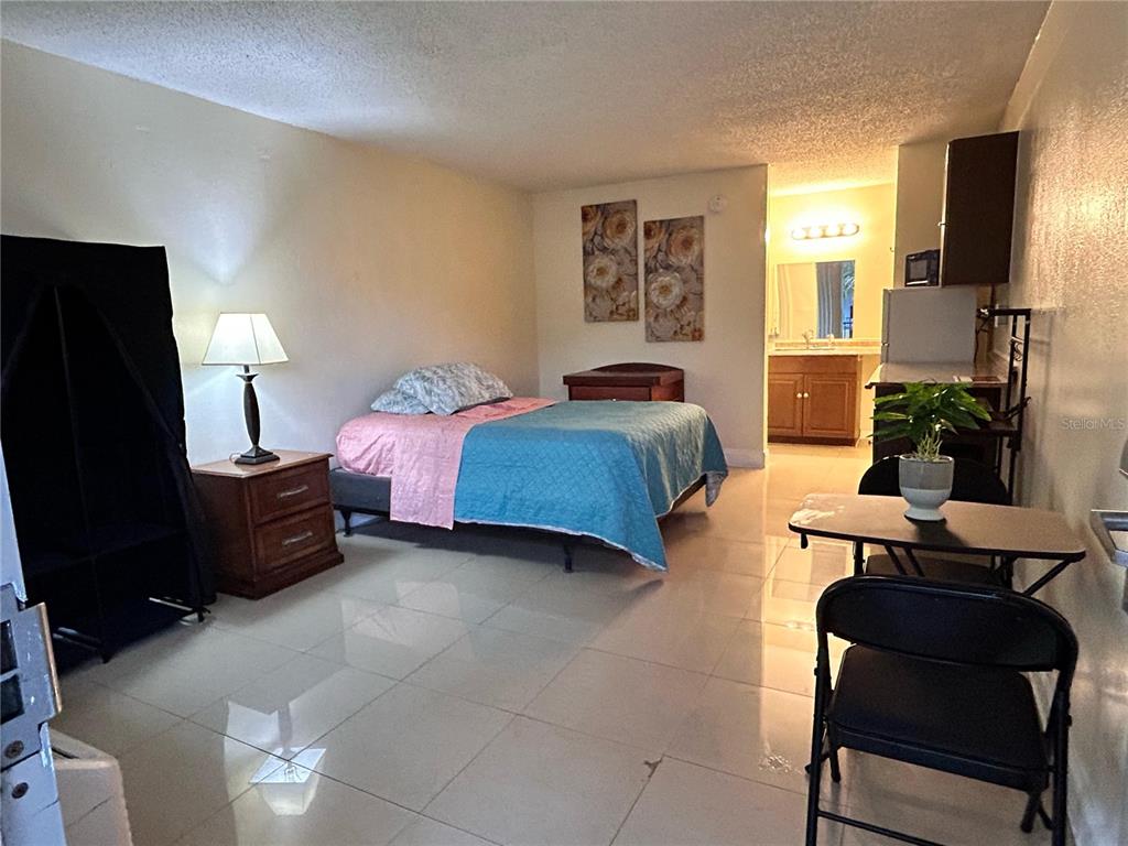 This studio apartment features a bed, a small dining table, and an adjacent bathroom — 7900 S ORANGE BLOSSOM TRAIL UNIT 2102, ORLANDO, FL