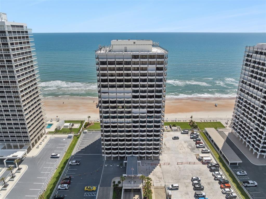 A balcony with chairs overlooks the ocean and a neighboring high-rise building — 2900 N ATLANTIC AVENUE UNIT 1106, DAYTONA BEACH, FL