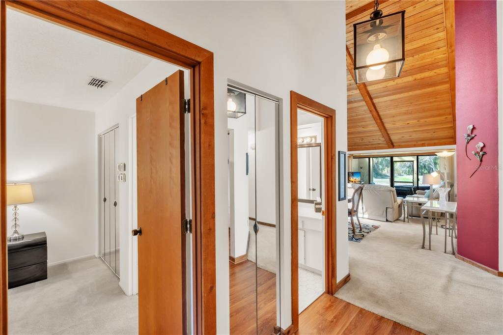 A hallway with wood-trimmed doorways leads to a living area with a vaulted wood ceiling — 7625 4TH AVENUE W UNIT 7625, BRADENTON, FL