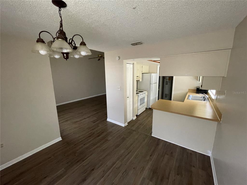 An open-concept dining area with a chandelier leads to a kitchen with laminate countertops — 750 ZELLA LANE, LAKELAND, FL
