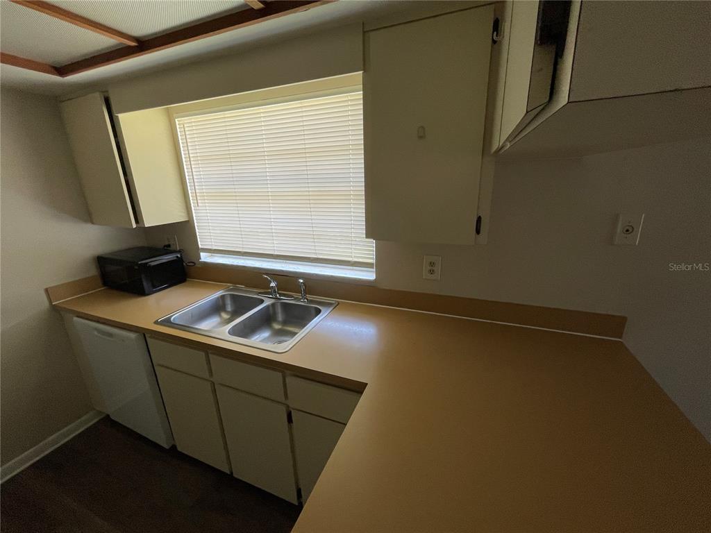 A kitchen features a double-basin sink, laminate countertops, white cabinets, and a dishwasher — 750 ZELLA LANE, LAKELAND, FL