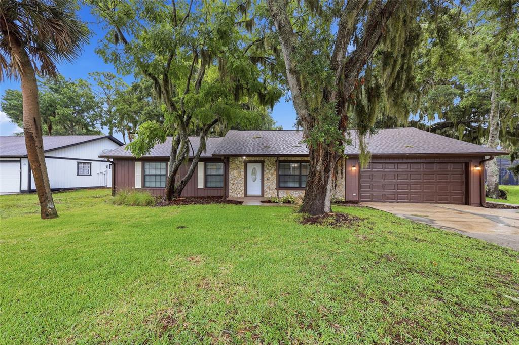 A single-story house with brown siding, a stone facade, and a two-car garage — 483 SPRUCEVIEW DRIVE, PORT ORANGE, FL