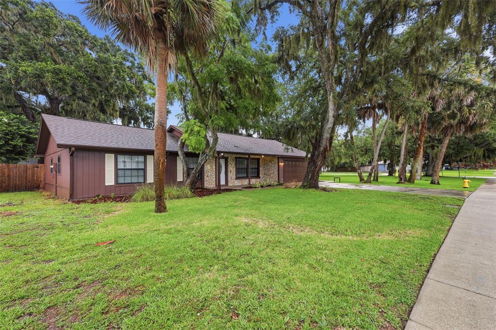 A single-story brown house with a stone facade and a large front lawn with trees — 483 SPRUCEVIEW DRIVE, PORT ORANGE, FL
