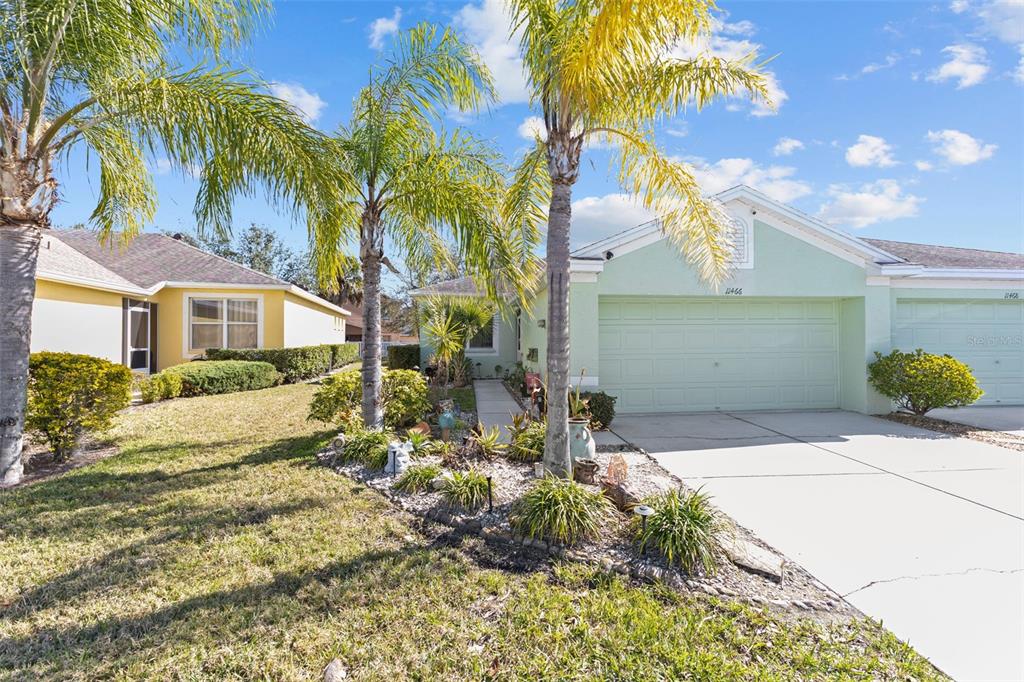 A light green house with a two-car garage and palm trees in the front yard — 11466 CAPTIVA KAY DRIVE, RIVERVIEW, FL