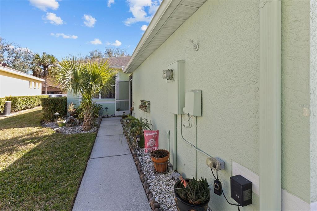 A concrete walkway leads along the side of a light green house toward a screened entrance — 11466 CAPTIVA KAY DRIVE, RIVERVIEW, FL
